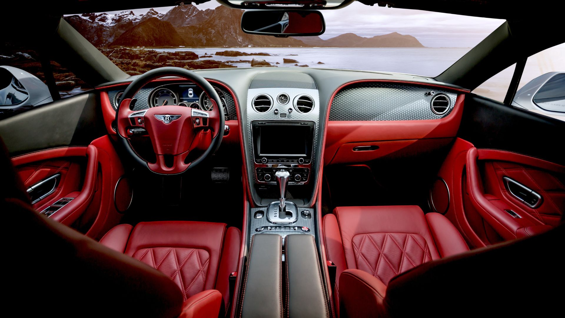 Luxurious red leather interior of a Bentley with mountain landscape view