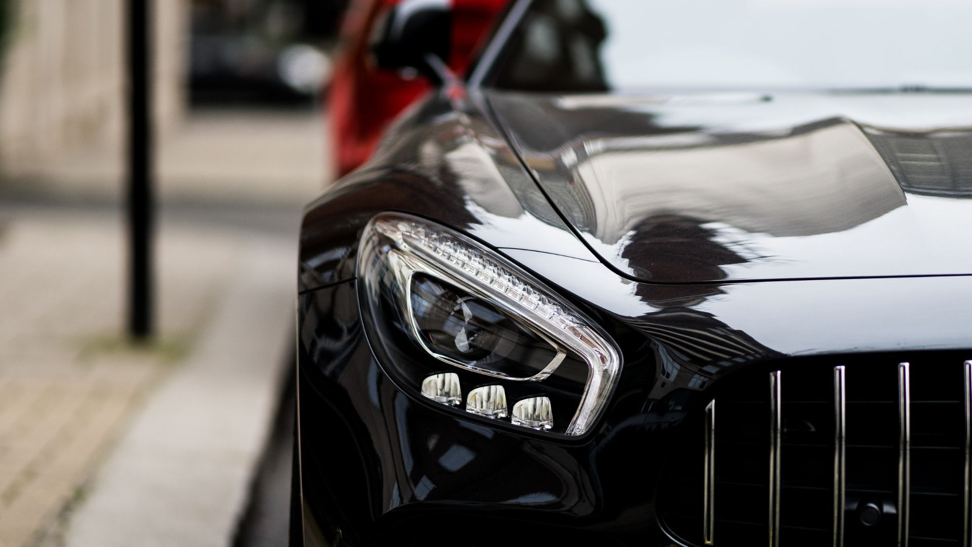 Close-up of sleek black luxury car headlight with reflective surface