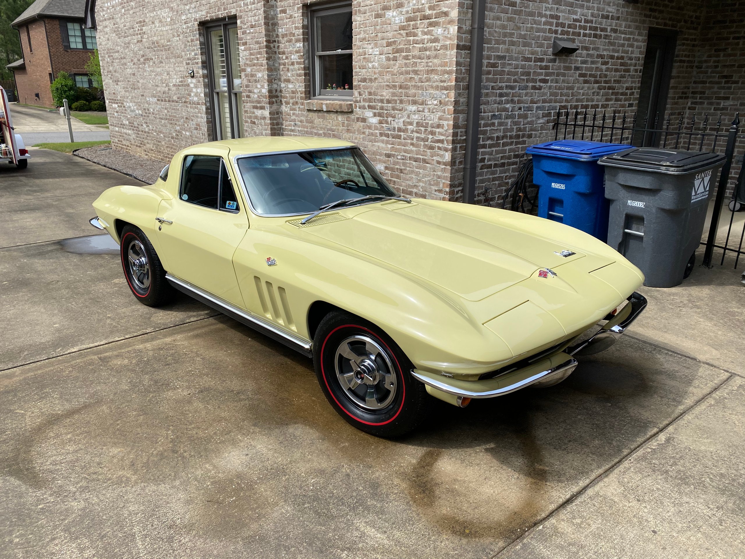Classic yellow 1960s Corvette Stingray parked on residential driveway