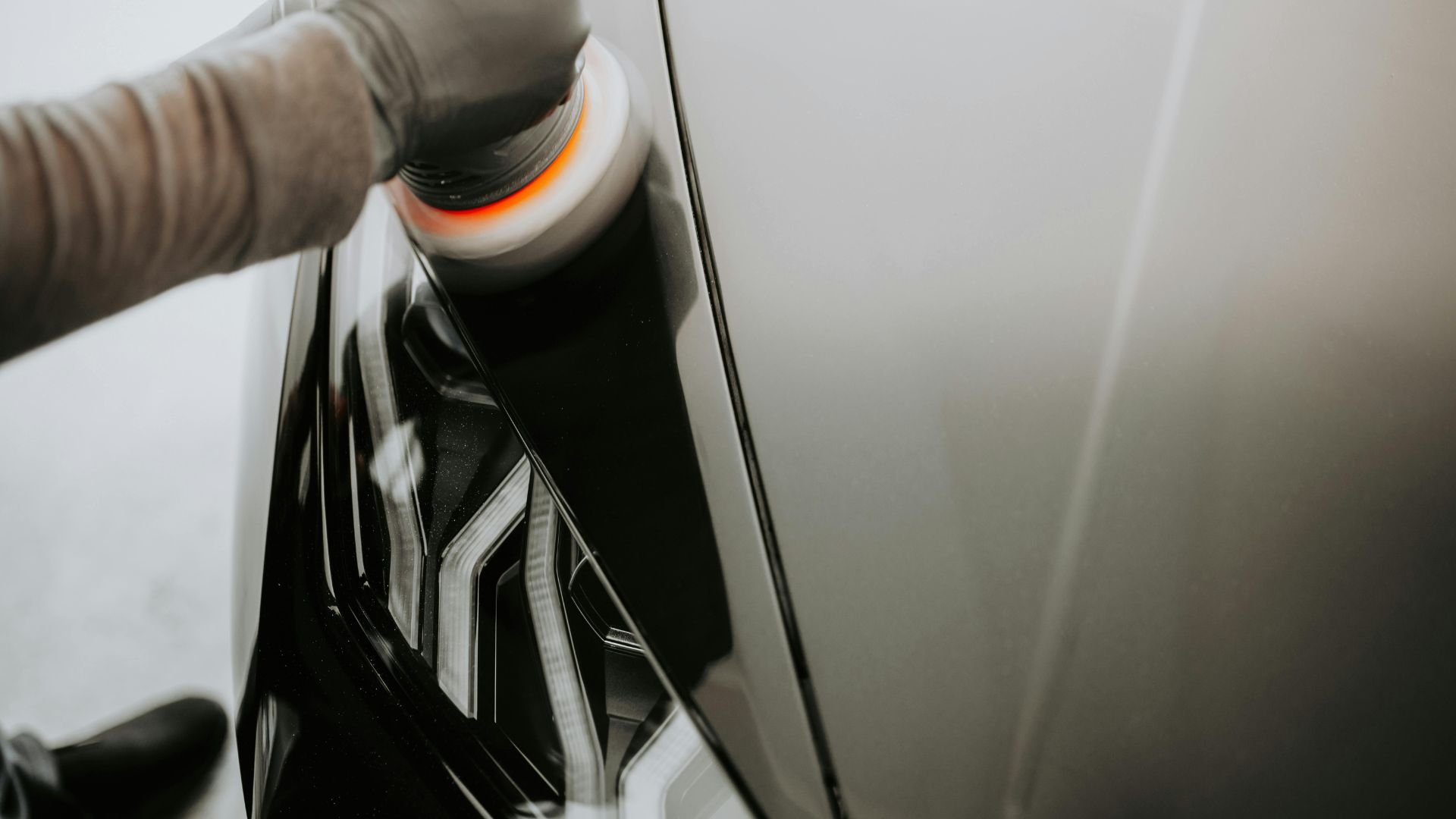 Polishing car wheel with glowing orange buffer and blurred background